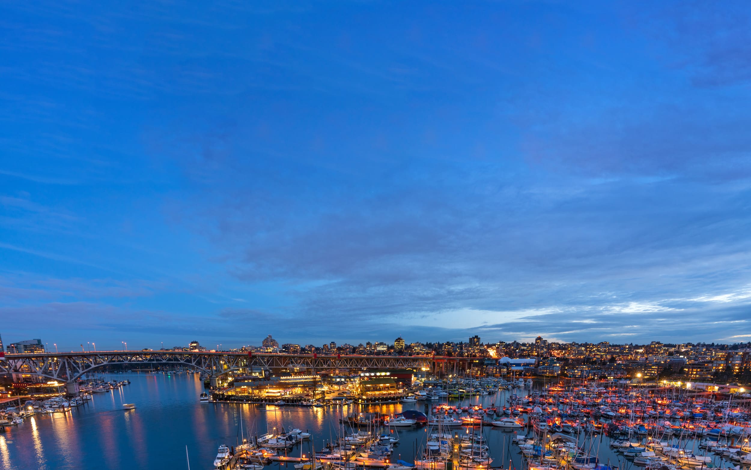 Aerial view of Granville Island in Vancouver at dusk. Many boats are in the marina.